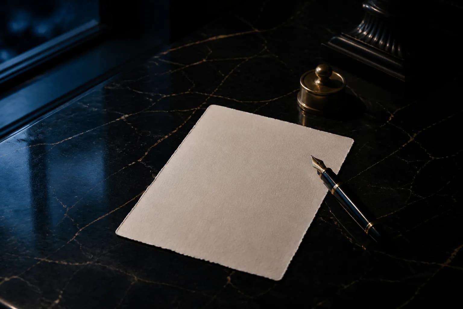 Editorial still life of cream paper and a fountain pen on dark veined marble